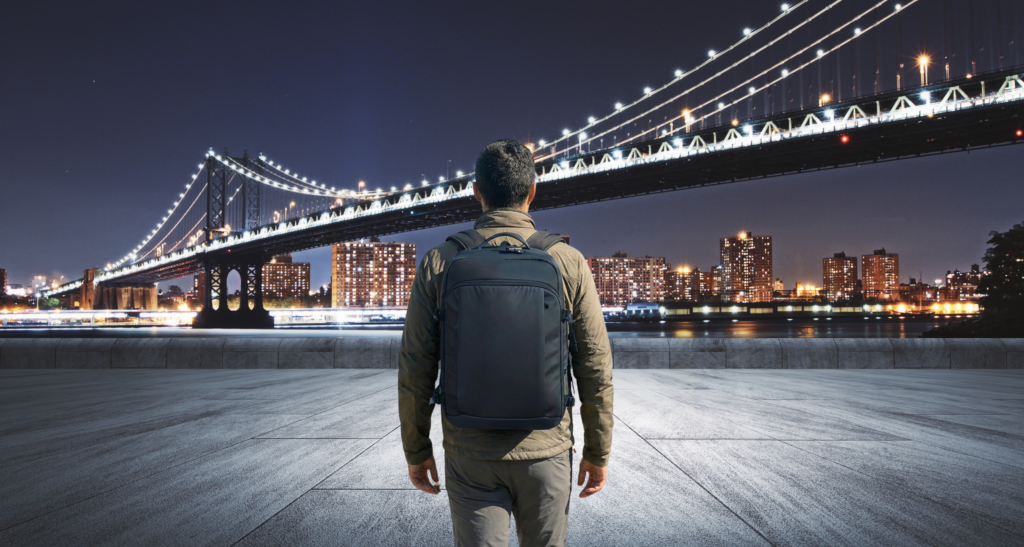 City life subject looking at a bridge while wearing bulletproof backpack